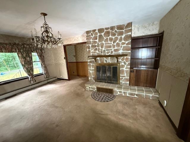 224 E Dunbarton Rd, Goffstown, NH 03045 - unfurnished living room featuring a chandelier, a stone fireplace, and wainscoting