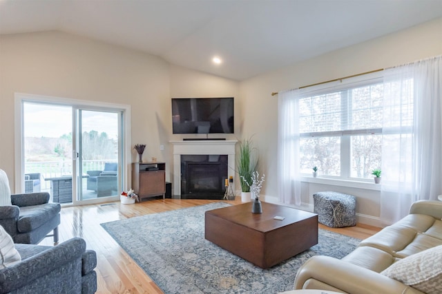 21 Catesby Ln, Londonderry, NH 03053 - living room featuring light wood-type flooring, vaulted ceiling, and a glass covered fireplace