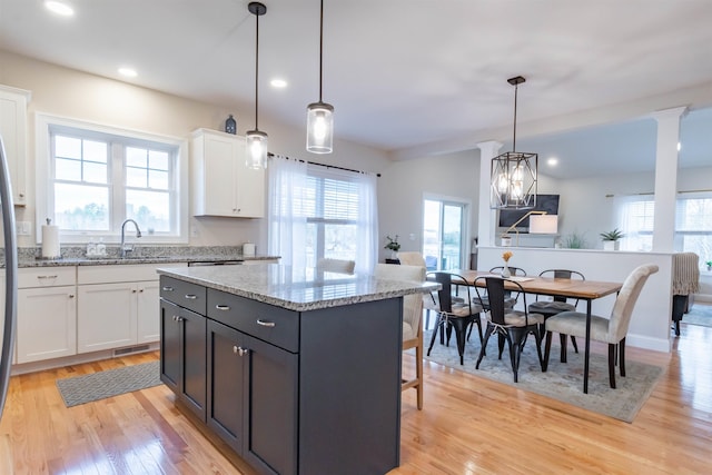 21 Catesby Ln, Londonderry, NH 03053 - kitchen featuring light wood-style flooring, white cabinetry, a breakfast bar area, a center island, and pendant lighting