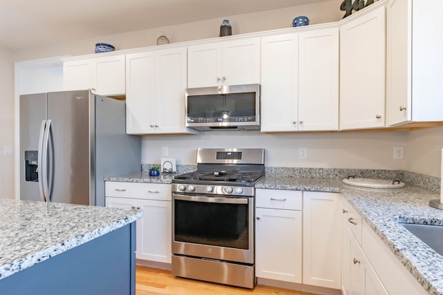 21 Catesby Ln, Londonderry, NH 03053 - kitchen featuring appliances with stainless steel finishes, white cabinets, light stone counters, and light wood-style floors
