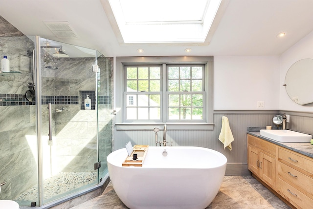 133 Hay Hill Rd, Francestown, NH 03043 - bathroom featuring a skylight, vanity, a stall shower, a soaking tub, and a wainscoted wall