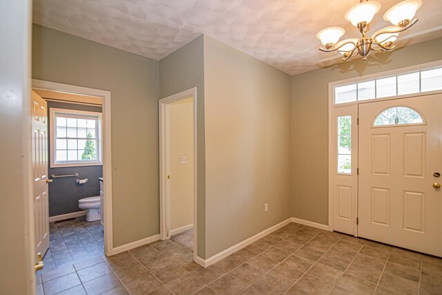32 Saint Andrews Way, Londonderry, NH 03053 - entryway with a chandelier, light tile patterned floors, and a textured ceiling