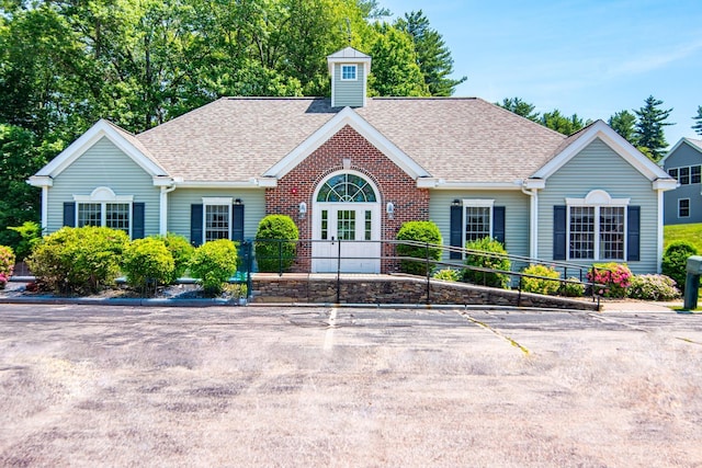 32 Saint Andrews Way, Londonderry, NH 03053 - view of front of property featuring french doors, a shingled roof, and brick siding