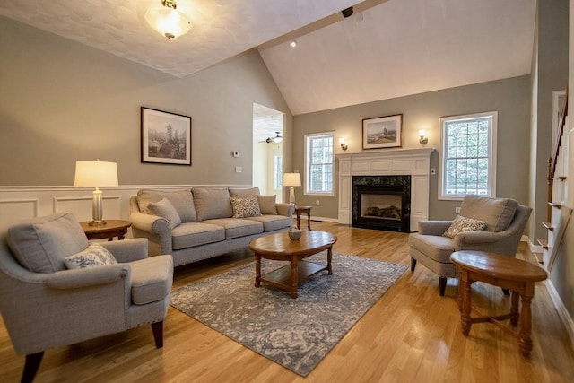 32 Saint Andrews Way, Londonderry, NH 03053 - living area with light wood-type flooring, plenty of natural light, a premium fireplace, high vaulted ceiling, and a wainscoted wall