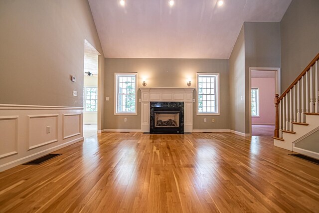 32 Saint Andrews Way, Londonderry, NH 03053 - unfurnished living room with stairway, light wood-type flooring, healthy amount of natural light, high vaulted ceiling, and a premium fireplace