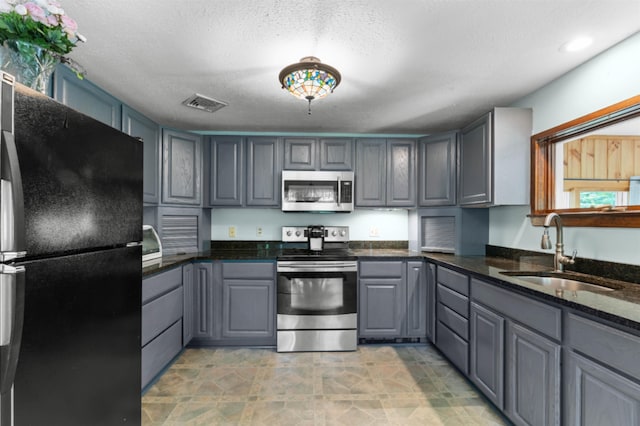 70 Tabor Cir, Albany, NH 03818 - kitchen with stainless steel appliances, gray cabinetry, dark stone countertops, and a textured ceiling