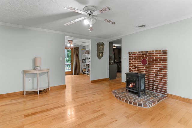 70 Tabor Cir, Albany, NH 03818 - living room featuring a ceiling fan, wood finished floors, a wood stove, ornamental molding, and a textured ceiling