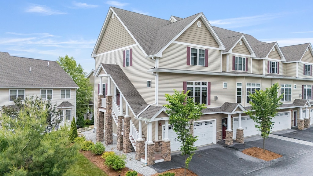11 Manor Dr Unit D, Hooksett, NH 03106 - multi unit property with driveway, an attached garage, stone siding, roof with shingles, and a residential view