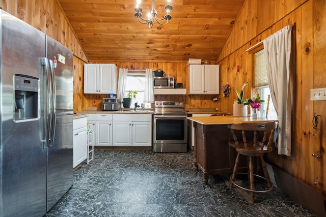 11 Providence Ave, Claremont, NH 03743 - kitchen featuring stainless steel appliances, lofted ceiling, wood walls, a chandelier, and white cabinetry