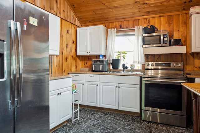 11 Providence Ave, Claremont, NH 03743 - kitchen with appliances with stainless steel finishes, wooden walls, vaulted ceiling, wood ceiling, and white cabinets