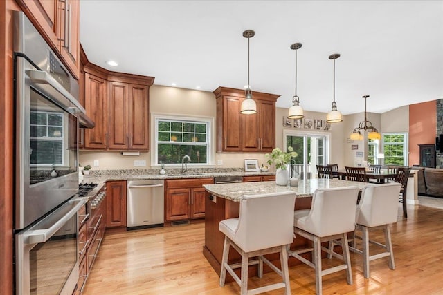 74 Settlers Ct, Bedford, NH 03110 - kitchen featuring stainless steel dishwasher, brown cabinets, a breakfast bar, light wood-style flooring, and a center island
