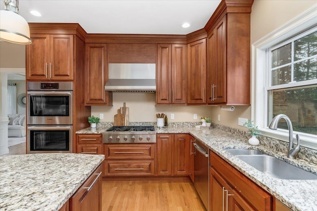 74 Settlers Ct, Bedford, NH 03110 - kitchen featuring stainless steel appliances, wall chimney range hood, brown cabinetry, and recessed lighting