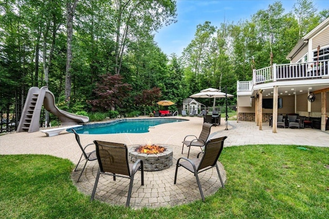 74 Settlers Ct, Bedford, NH 03110 - swimming pool with a water slide, an outdoor living space with a fire pit, a patio, a lawn, and view of wooded area