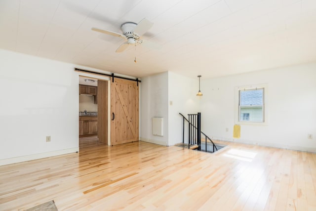 11 Bridge St, Kittery, ME 03904 - unfurnished living room featuring a barn door, light wood finished floors, and a ceiling fan