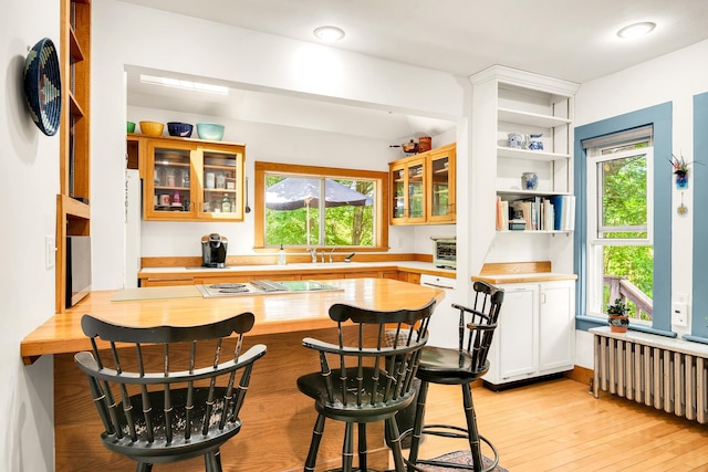 175 Middle Rd, Portsmouth, NH 03801 - kitchen with radiator heating unit, stovetop with downdraft, wood counters, a kitchen breakfast bar, and glass insert cabinets