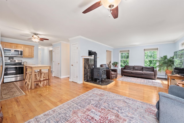 202 Cherry Valley Rd, Alton, NH 03810 - living room with ceiling fan, a wood stove, light wood finished floors, ornamental molding, and a baseboard heating unit