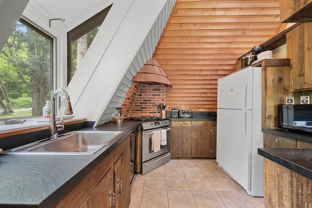 812 Airport Rd, Fayston, VT 05660 - kitchen with stainless steel range with gas stovetop, freestanding refrigerator, light tile patterned flooring, and dark countertops