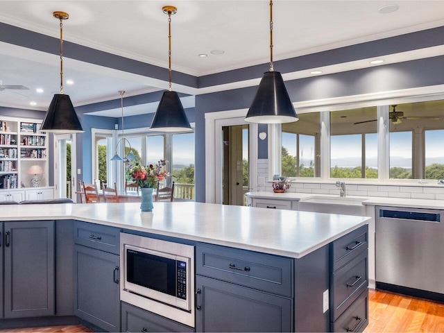 1411 Spear St, South Burlington, VT 05403 - kitchen featuring appliances with stainless steel finishes, ceiling fan, light countertops, crown molding, and hanging light fixtures