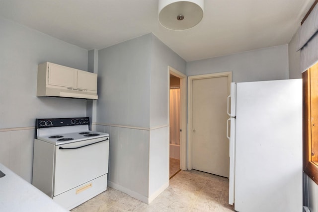 102 W Merrimack St Unit 1, Manchester, NH 03101 - kitchen with white appliances, under cabinet range hood, a wainscoted wall, light countertops, and white cabinetry