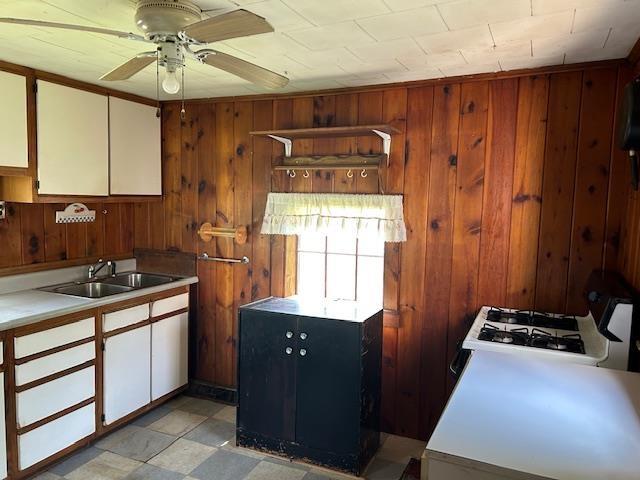 310 Nh Route 119th Rte, Fitzwilliam, NH 03461 - kitchen featuring wooden walls, light countertops, ceiling fan, and white cabinetry