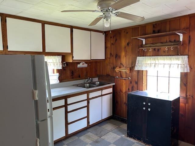 310 Nh Route 119th Rte, Fitzwilliam, NH 03461 - kitchen with freestanding refrigerator, ceiling fan, light countertops, white cabinetry, and wooden walls