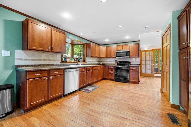 17 N Ave, Plaistow, NH 03865 - kitchen with appliances with stainless steel finishes, light wood-style flooring, tasteful backsplash, brown cabinets, and dark countertops