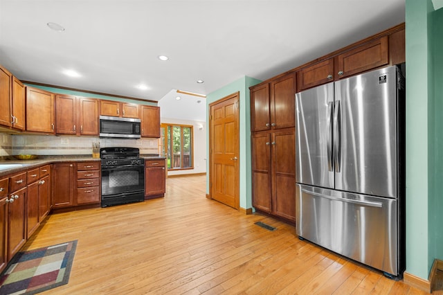 17 N Ave, Plaistow, NH 03865 - kitchen with stainless steel appliances, light wood-type flooring, backsplash, dark countertops, and brown cabinets