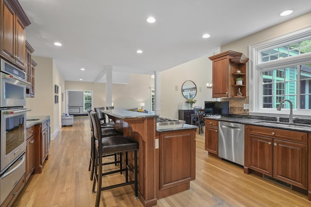 4 Chablis Ct, Bedford, NH 03110 - kitchen with appliances with stainless steel finishes, a warming drawer, light wood finished floors, a breakfast bar area, and tasteful backsplash