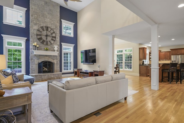 4 Chablis Ct, Bedford, NH 03110 - living area featuring ornate columns, light wood-type flooring, ceiling fan, a stone fireplace, and recessed lighting