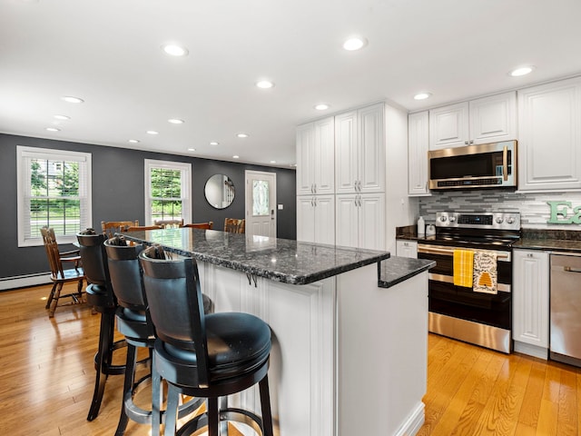 44 Mcquade Brook Rd, Bedford, NH 03110 - kitchen featuring stainless steel appliances, white cabinetry, light wood-style floors, a kitchen bar, and recessed lighting