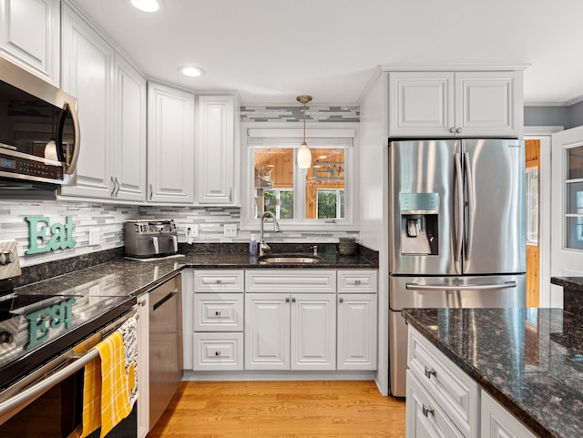 44 Mcquade Brook Rd, Bedford, NH 03110 - kitchen with appliances with stainless steel finishes, ornamental molding, white cabinetry, light wood-type flooring, and dark stone countertops
