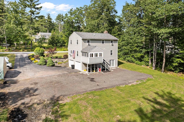 44 Mcquade Brook Rd, Bedford, NH 03110 - rear view of house featuring a chimney, asphalt driveway, a lawn, view of scattered trees, and roof with shingles