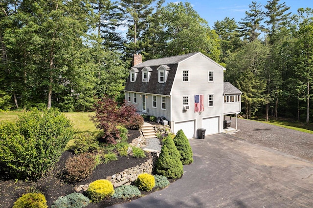 44 Mcquade Brook Rd, Bedford, NH 03110 - view of front of house with driveway, a chimney, a gambrel roof, a shingled roof, and an attached garage