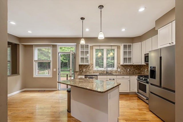 473 Brennan Woods Dr, Williston, VT 05495 - kitchen featuring stainless steel appliances, white cabinetry, decorative backsplash, glass insert cabinets, and healthy amount of natural light