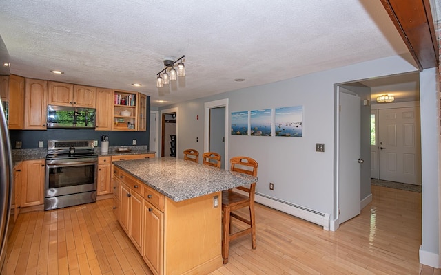 33 Hillside Rd, Kingston, NH 03848 - kitchen featuring appliances with stainless steel finishes, baseboard heating, a breakfast bar area, a textured ceiling, and a center island