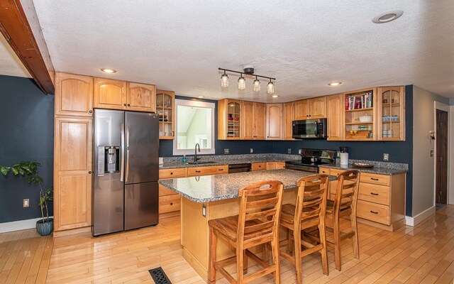 33 Hillside Rd, Kingston, NH 03848 - kitchen featuring appliances with stainless steel finishes, light wood-type flooring, a kitchen island, a textured ceiling, and a breakfast bar area