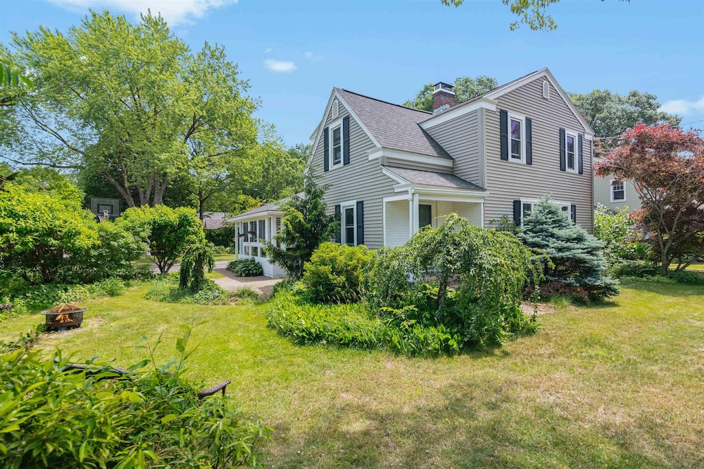 11 Beacon St, South Burlington, VT 05403 - view of property exterior with an outdoor fire pit, a shingled roof, a lawn, and a chimney