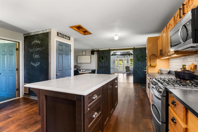 174 E Colebrook Rd, Colebrook, NH 03576 - kitchen with appliances with stainless steel finishes, dark wood-style floors, tasteful backsplash, and a kitchen island