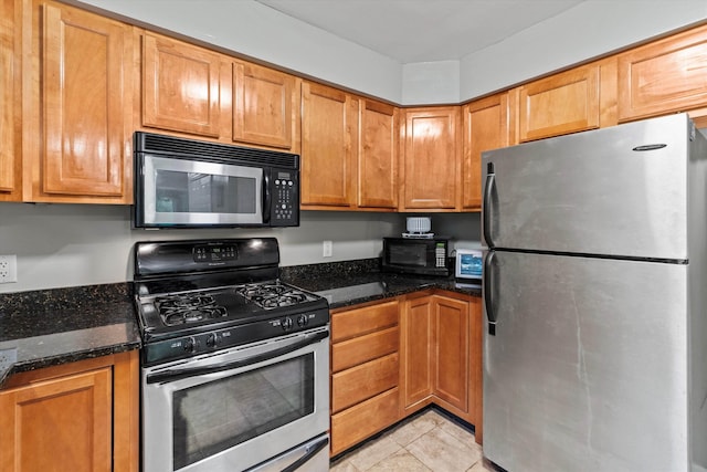 25 Sweetbrier Way, Laconia, NH 03246 - kitchen with stainless steel appliances, dark stone counters, light tile patterned flooring, and brown cabinets