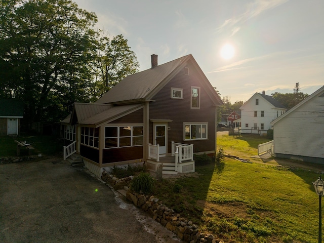 24 Church St, Wakefield, NH 03872 - view of front facade with a sunroom, a chimney, and a front lawn