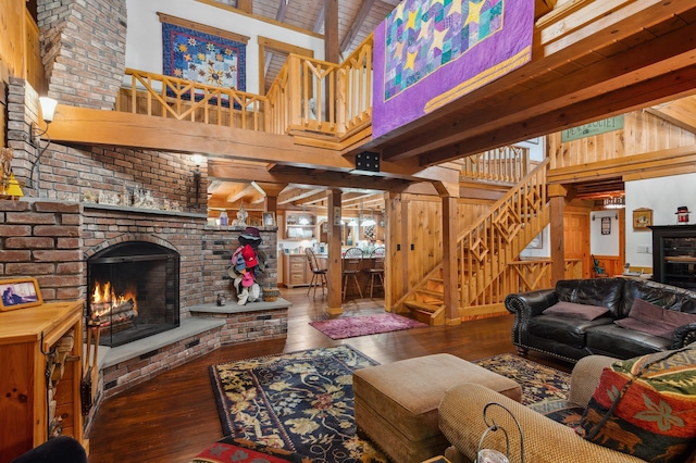 7 Reidy Way, Littleton, NH 03561 - living room featuring high vaulted ceiling, wood walls, stairs, hardwood / wood-style floors, and a brick fireplace