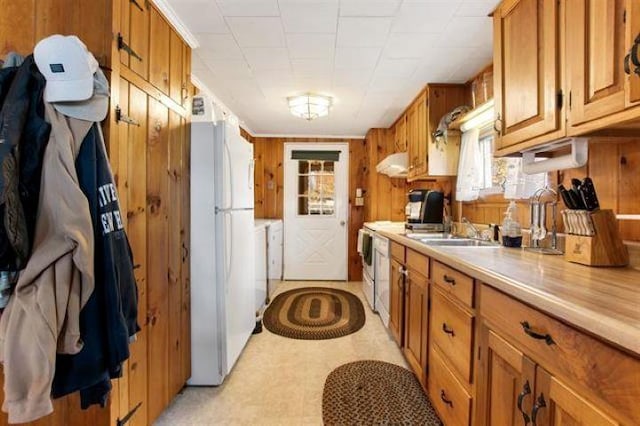 124 Spooner Rd, Pittsburg, NH 03592 - kitchen featuring freestanding refrigerator, brown cabinetry, light countertops, wood walls, and washing machine and clothes dryer