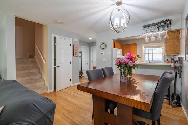 19 Village Falls Way, Merrimack, NH 03054 - dining area with light wood-type flooring, stairs, a chandelier, and a textured ceiling