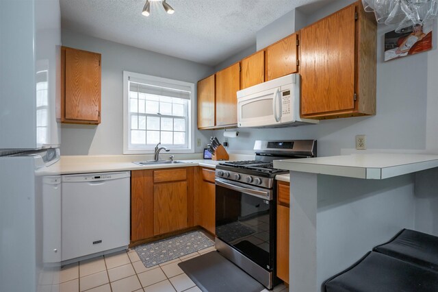 19 Village Falls Way, Merrimack, NH 03054 - kitchen with white appliances, brown cabinets, light countertops, a peninsula, and a textured ceiling