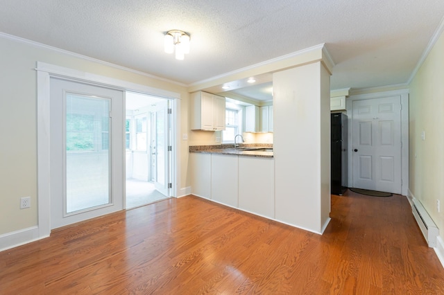 126 Flintlock Vlg Unit 3, Wells, ME 04090 - kitchen featuring ornamental molding, light wood finished floors, white cabinets, a baseboard radiator, and a textured ceiling