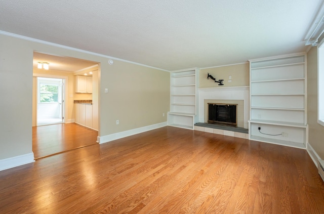 126 Flintlock Vlg Unit 3, Wells, ME 04090 - unfurnished living room with a tiled fireplace, built in shelves, wood finished floors, ornamental molding, and a textured ceiling