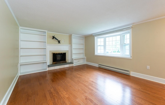 126 Flintlock Vlg Unit 3, Wells, ME 04090 - unfurnished living room with a baseboard radiator, crown molding, a tiled fireplace, wood finished floors, and built in features