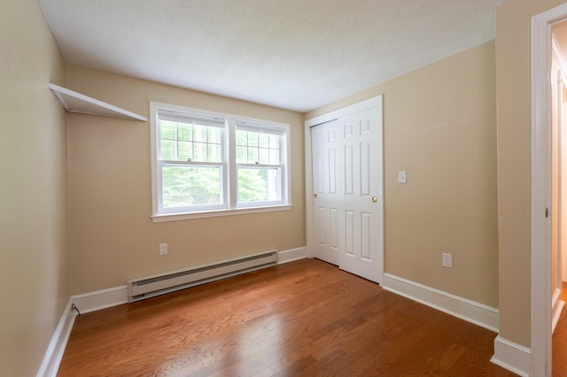 126 Flintlock Vlg Unit 3, Wells, ME 04090 - unfurnished bedroom with a baseboard heating unit, wood finished floors, a closet, and a textured ceiling