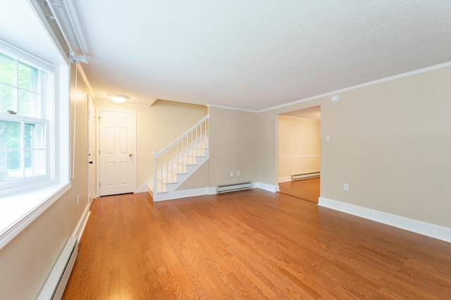 126 Flintlock Vlg Unit 3, Wells, ME 04090 - empty room featuring a baseboard heating unit, stairway, light wood finished floors, crown molding, and a textured ceiling