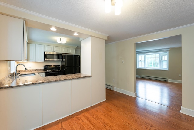 126 Flintlock Vlg Unit 3, Wells, ME 04090 - kitchen with black appliances, a baseboard radiator, crown molding, a textured ceiling, and light wood-type flooring
